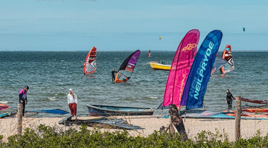windsurfers on the water with flags on the beach